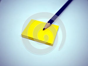 Blue pencil on yellow sticky note