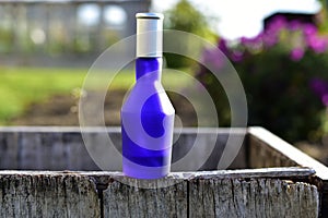 Blue perfume bottle on the background of flowers in the garden