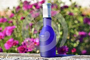 Blue perfume bottle on the background of flowers in the garden