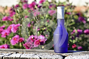 Blue perfume bottle on the background of flowers in the garden