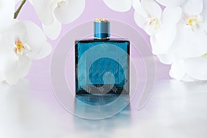 Blue perfume bottle in the midst of the white Orchid in pink pastel background