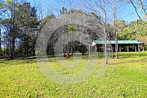 A blue pergola in the park with lush green grass and yellow signs along a footpath