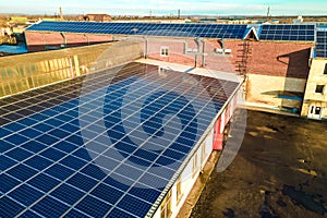 Blue photovoltaic solar panels mounted on industrial building roof for producing clean ecological electricity