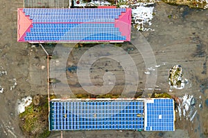 Blue photovoltaic solar panels mounted on industrial building roof for producing clean ecological electricity. Production of