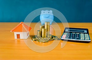 Blue pig bank and coins stack and yellow paper house