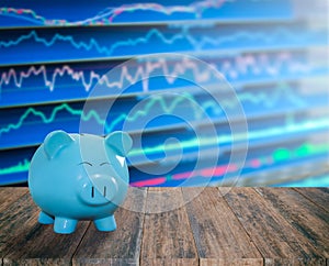 blue pig bank on wood background with blur stock market background,money and saving concept.
