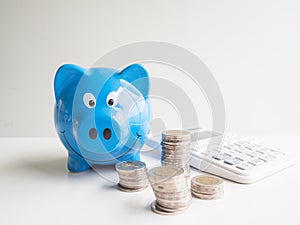 Blue Piggy bank and calculator  with coins pile, Saving money for future plan and retirement fund concept