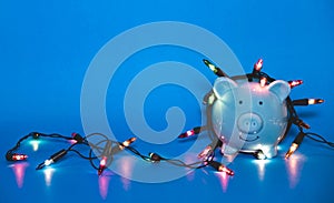 Blue piggy bank with Christmas string lights on happy December festival, Enjoy savings for spending money on the holiday`s concep