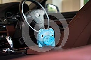 Blue piggy bank money box inside a car vehicle