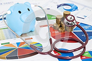 Blue piggy bank and stethoscope checking stack of money coins