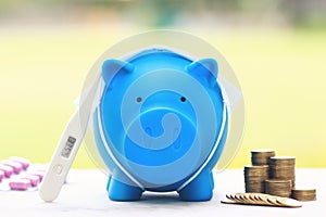 Blue piggy with thermometer and medicine on natural green background,Save money for Medical expenses and Health care concept