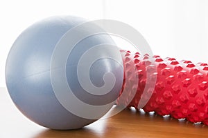 A blue pilates ball and a red fascial massage roller