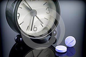 Blue pills next to a clock