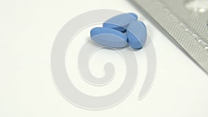 Blue pills for treating impotence or erectile dysfunction on a white table.
