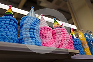 Blue and pink paper cones, hats for birthday party with fluffy pompons for festive holiday celebration standing on supermarket