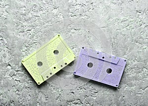 Blue and pink pastel audio cassettes on a gray