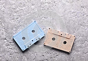 Blue and pink pastel audio cassettes on a gray concrete