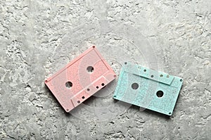 Blue and pink pastel audio cassettes on a gray concrete background. Top view, copy space.