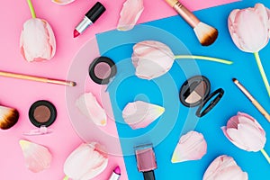 Blue and pink pastel background with flowers and make up cosmetics. Flat lay. Top view