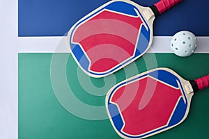 Blue and pink pickleball paddles isolated on playing court