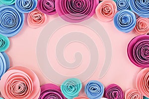 Blue and pink rose flat lay background with crafted paper flowers around border and empty pastel pink copy space