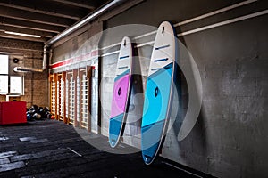 Blue and pink stand-up paddle boards SUP by the wall. Surfing and sup boarding equipment close up photo