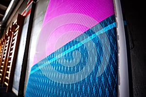 Blue and pink stand-up paddle boards SUP by the wall. Surfing and sup boarding equipment close up photo