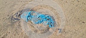 Blue plastic bag pollution on sea beach endangering marine life