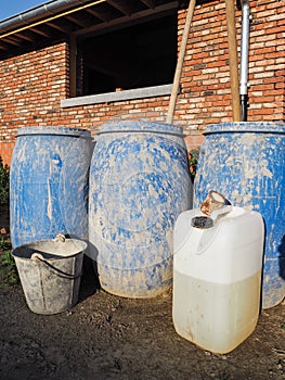 Blue plastic barrels, white can and metal bucket used on a construction site