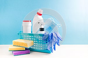 in a blue plastic basket are different plastic bottles with cleaning products