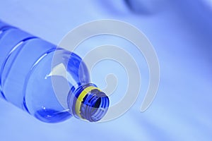 A blue plastic bottle water with yellow bottle cap on blue sky background