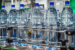 Blue plastic bottles of clean drinking water on a conveyor belt. Food production