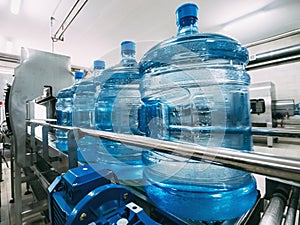 Blue plastic bottles with purified drinking water on automated conveyor production line. Water factory