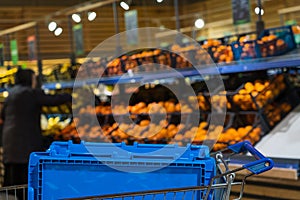 Blue plastic box for picking up a delivery order in a store grocery cart with selective focus. Background