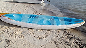 Blue plastic canoe boat pulled ashore at the beach