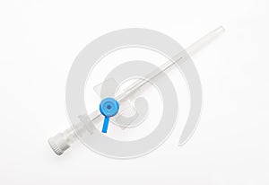 Blue plastic catheter with needle closed by protective cap isolated on white