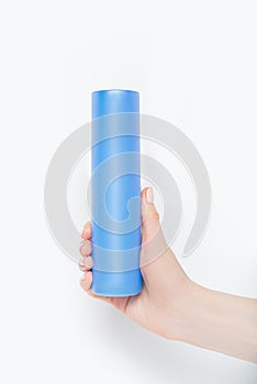 Blue plastic container for cosmetics in a female hand. White background