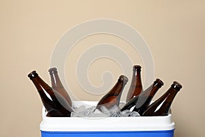 Blue plastic cool box with ice cubes and beer on beige background, closeup. Space for text