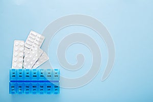 Blue plastic 14 day pill box with pills on blue background. Top view