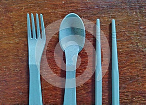 blue plastic fork,chopsticks,and spoon on wooden background