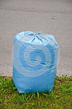 Blue plastic garbage bag on street