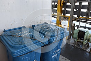 Blue plastic garbage bins for food waste firmly tight to the railings are situated behind superstructure photo