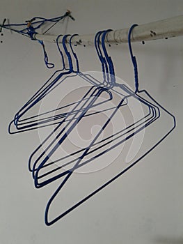Blue plastic hangers hnaging on a white pipe