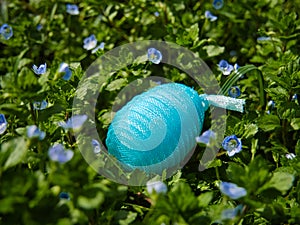 Blue Plastic nylon Easter egg among garden flowers