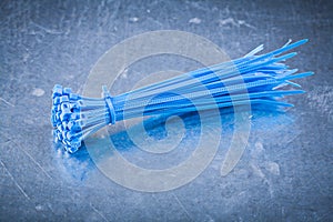 Blue plastic self-locking cable ties on metallic background cons