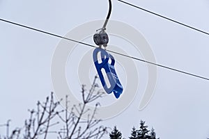 Blue plastic sled is hanging on a toboggan lift