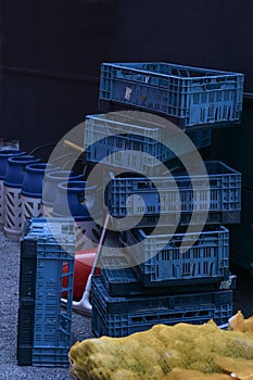 Blue plastic transport boxes, potato sack and barrels for gas bottles at the back of a chip shop food track, dark background, copy