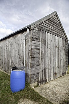 Blue plastic water attached to wooden shed