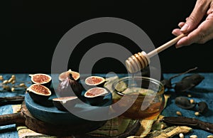 Plate with three cut figs and one whole and container with honey photo