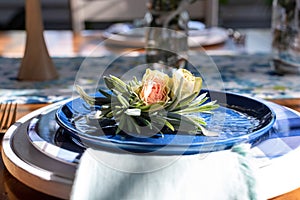 Blue plate topped with roses on a table decorated for spring
